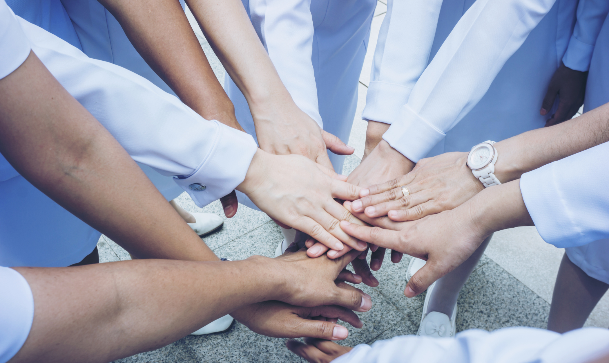 Nurses putting their hands together in a huddle
